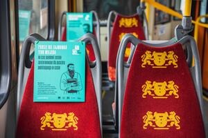 Wnętrze tramwaju, widać siedzenia pokryte bordową tkaniną z wzorem w postaci herbów Gdańska. Na co drugim siedzeniu jest seledynowa prostokątna karta z wizerunkiem nieżyjącej już postaci związanej z historią gdańskiej biblioteki i napis, ze to miejsce przeznaczone jest dla osoby podróżującej w czasie