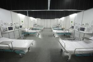 szpitalne pomieszczenie, puste, pod ściankami stoją łóżka szpitalne